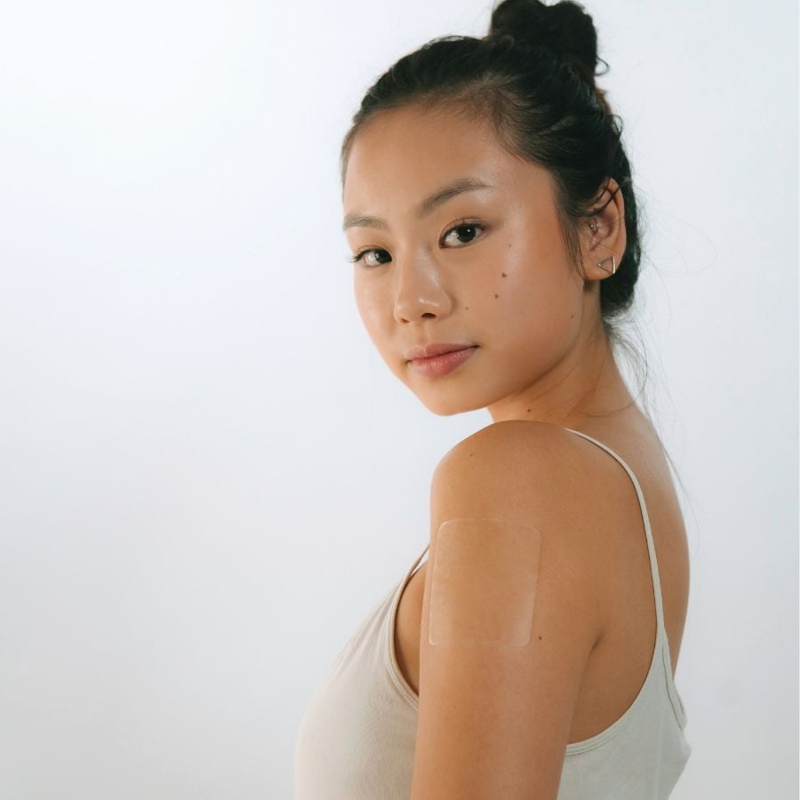 Asian woman with a transparent Glowless alcohol flush patch applied to her shoulder, side profile