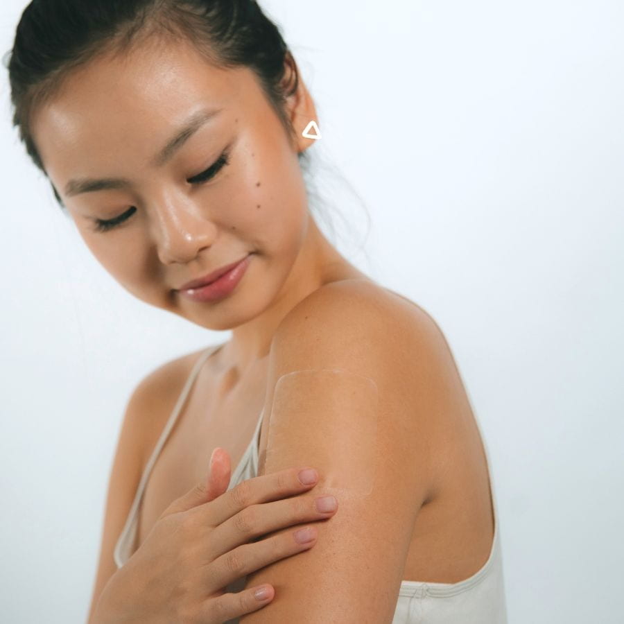 Asian woman wearing a Glowless alcohol flush patch on her shoulder before going out