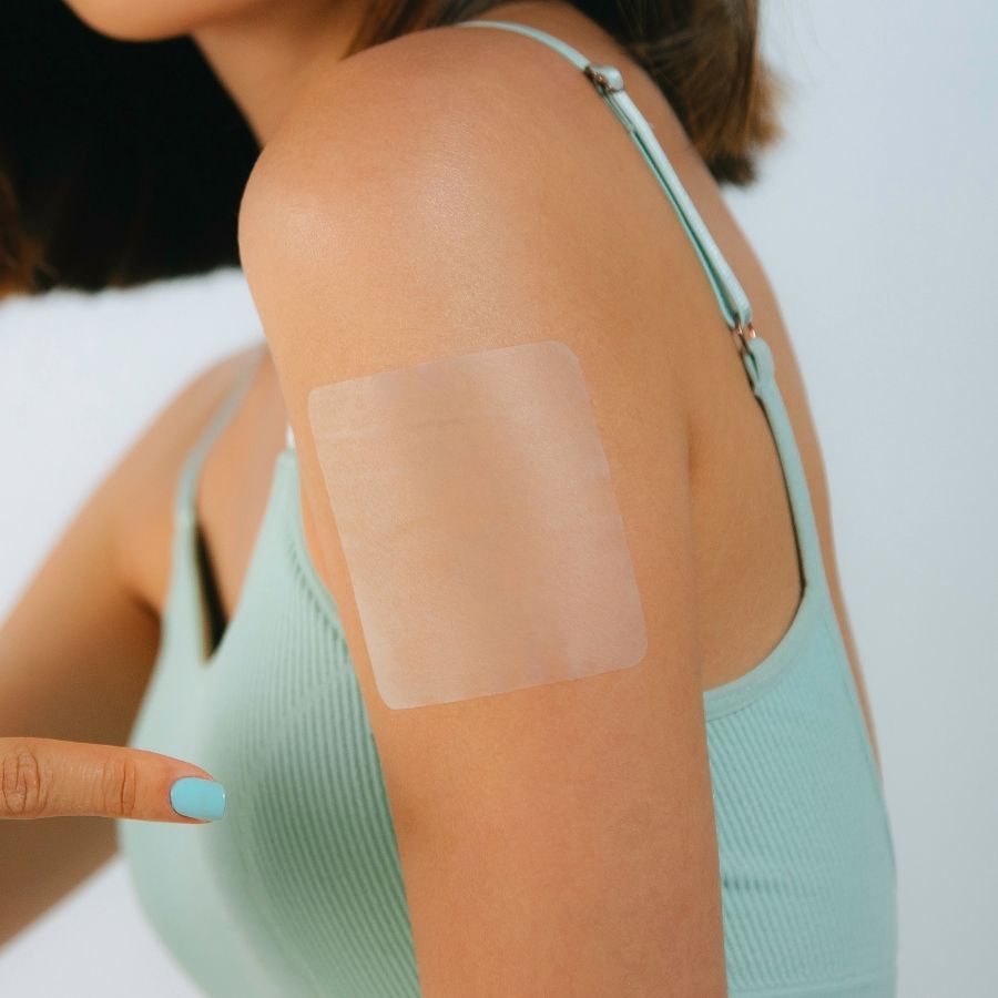 Transparent Glowless Asian glow patch applied to a woman’s upper arm, nearly invisible on skin